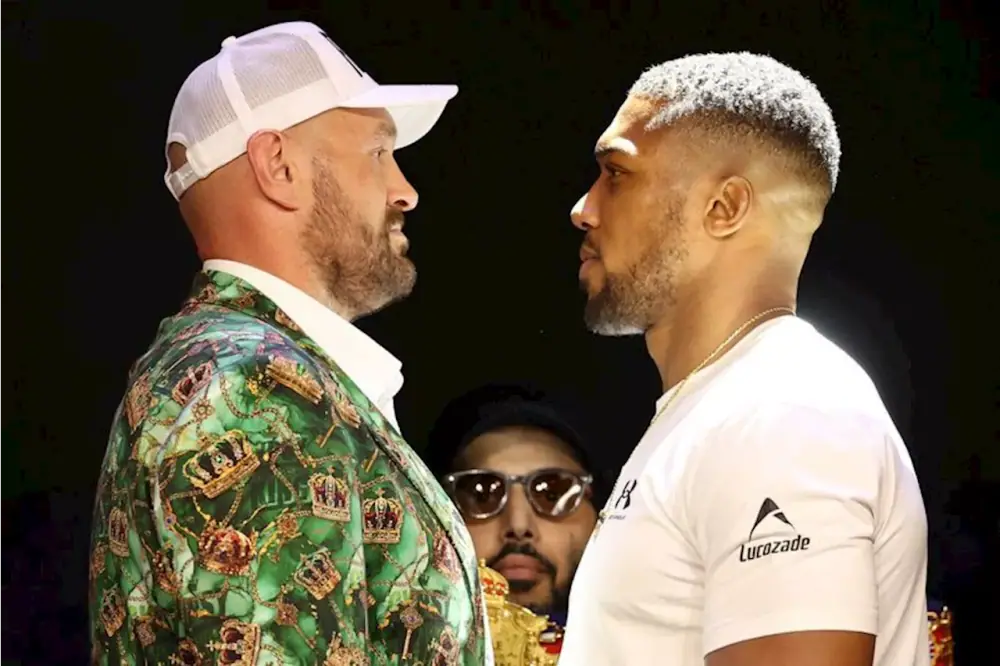 Tyson Fury in a green crown-print jacket facing Anthony Joshua in a white shirt at a press face-off